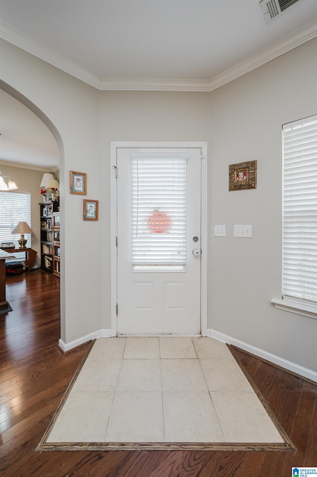 foyer entrance with hardwood / wood-style floors, crown molding, and a chandelier