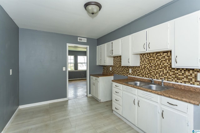 7749 5th Ave, Birmingham, AL 35206 - kitchen featuring a sink, tasteful backsplash, white cabinetry, and baseboards