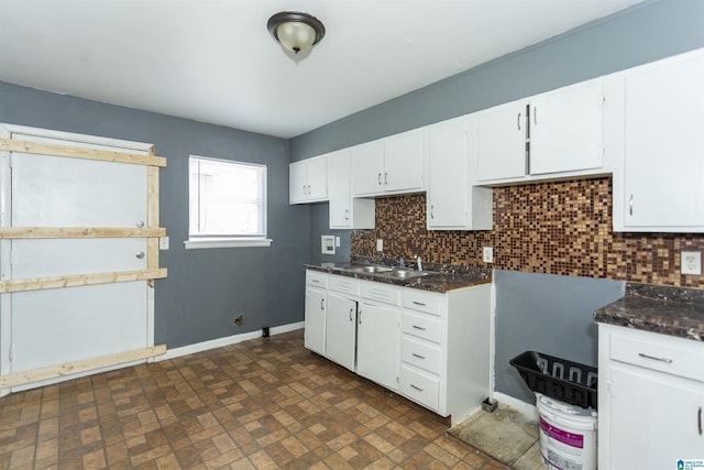 7749 5th Ave, Birmingham, AL 35206 - kitchen with a sink, backsplash, white cabinets, and baseboards