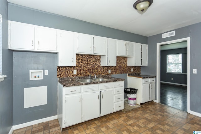 7749 5th Ave, Birmingham, AL 35206 - kitchen with baseboards, a sink, white cabinets, and decorative backsplash