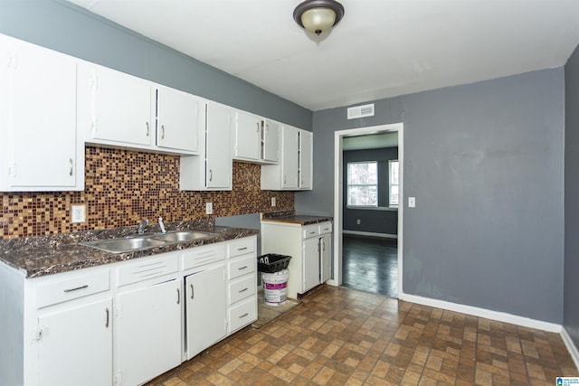 7749 5th Ave, Birmingham, AL 35206 - kitchen with a sink, baseboards, dark countertops, backsplash, and brick patterned flooring