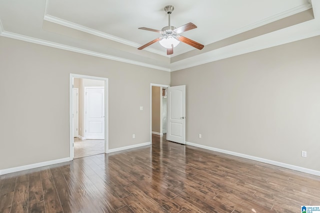 empty room featuring ornamental molding, ceiling fan, a raised ceiling, and dark hardwood / wood-style flooring