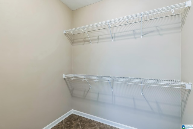 walk in closet with dark tile patterned flooring