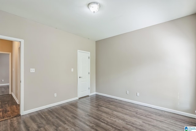 empty room featuring dark wood finished floors and baseboards