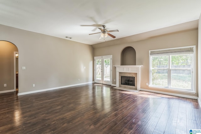 unfurnished living room featuring ceiling fan, a fireplace, and dark wood-type flooring