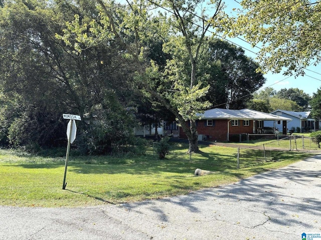view of front of house with brick siding, a front lawn, and fence
