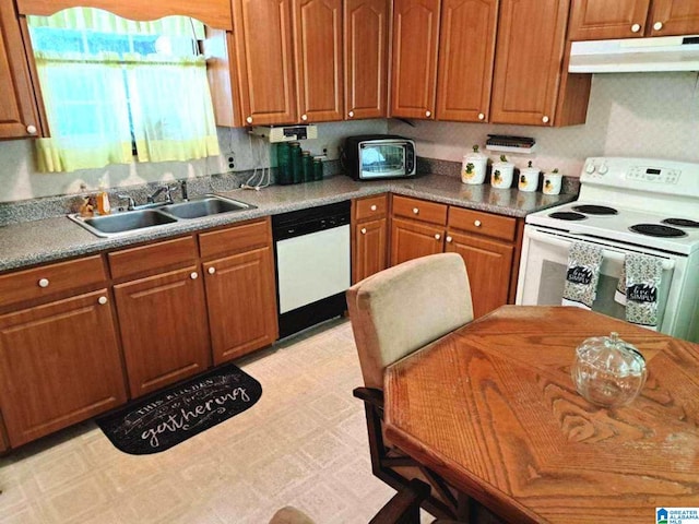 kitchen with under cabinet range hood, white appliances, a sink, and light floors