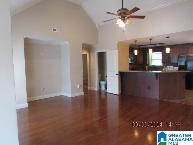 kitchen featuring ceiling fan, kitchen peninsula, high vaulted ceiling, dark hardwood / wood-style floors, and black refrigerator