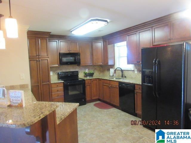 kitchen with hanging light fixtures, kitchen peninsula, a breakfast bar area, black appliances, and sink