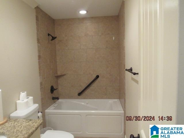 full bathroom with vanity, tiled shower / bath combo, and toilet