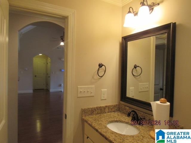 bathroom featuring ceiling fan, vanity, crown molding, and hardwood / wood-style floors