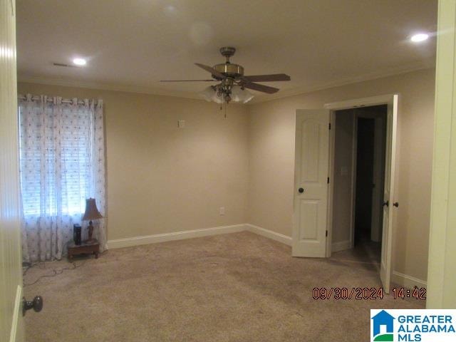 carpeted spare room featuring ceiling fan and ornamental molding