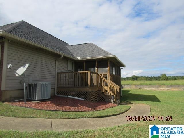 view of property exterior with a deck, a sunroom, a yard, and central air condition unit