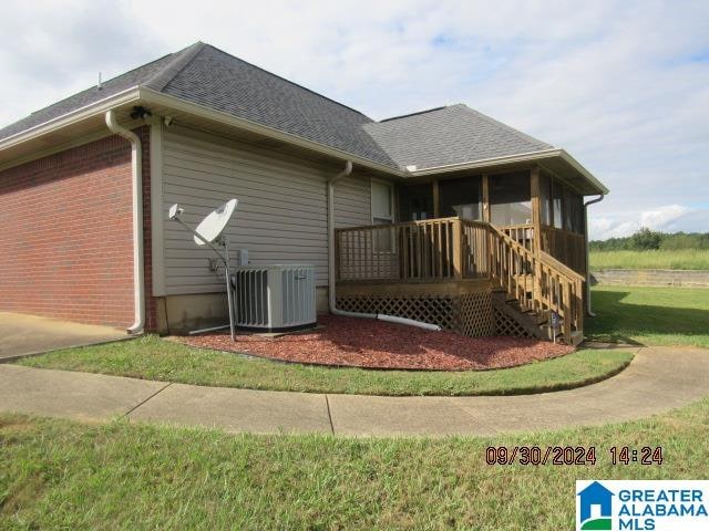 view of side of home featuring a lawn, cooling unit, and a sunroom