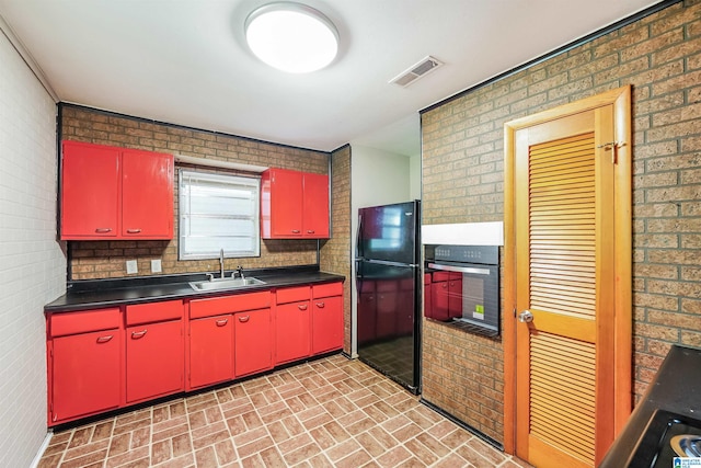 kitchen with black appliances, sink, and brick wall