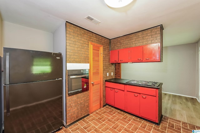 kitchen with brick wall, hardwood / wood-style floors, and black appliances