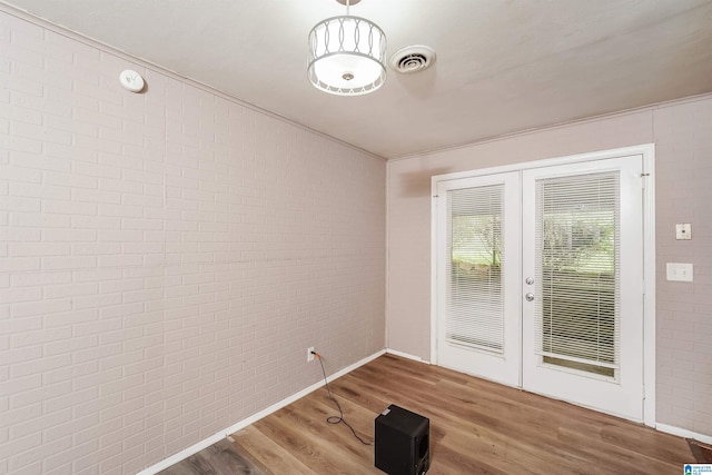 spare room with brick wall, hardwood / wood-style flooring, and crown molding