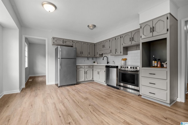 kitchen featuring sink, light hardwood / wood-style flooring, stainless steel appliances, gray cabinetry, and decorative backsplash