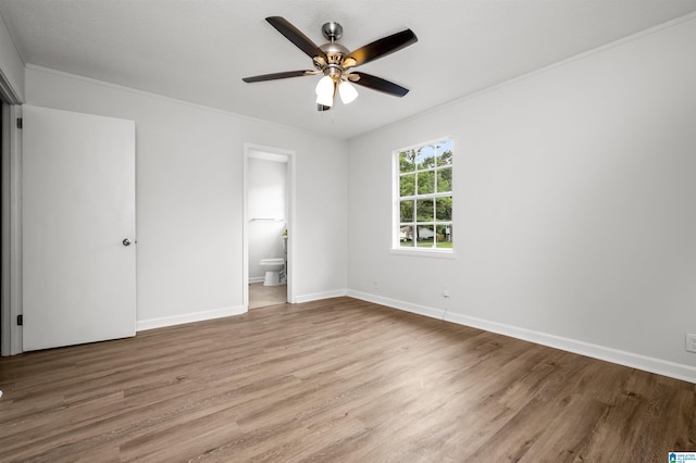 unfurnished bedroom with crown molding, ceiling fan, ensuite bathroom, and hardwood / wood-style flooring