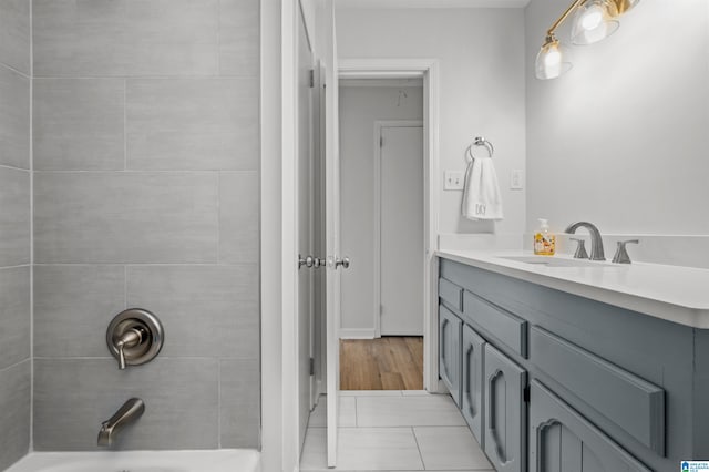 bathroom featuring tile patterned flooring, tiled shower / bath combo, and vanity