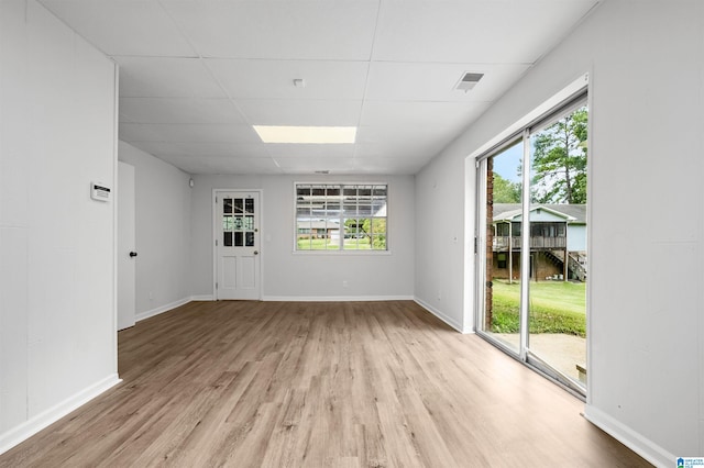 empty room with light hardwood / wood-style flooring and a drop ceiling