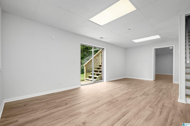 empty room with light hardwood / wood-style flooring and a paneled ceiling