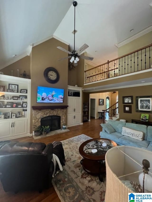 living room with ceiling fan, crown molding, dark wood-type flooring, a fireplace, and high vaulted ceiling