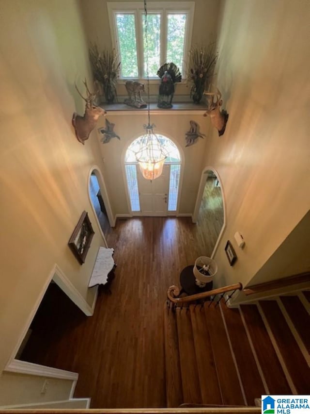 entryway with a towering ceiling, a chandelier, and hardwood / wood-style floors