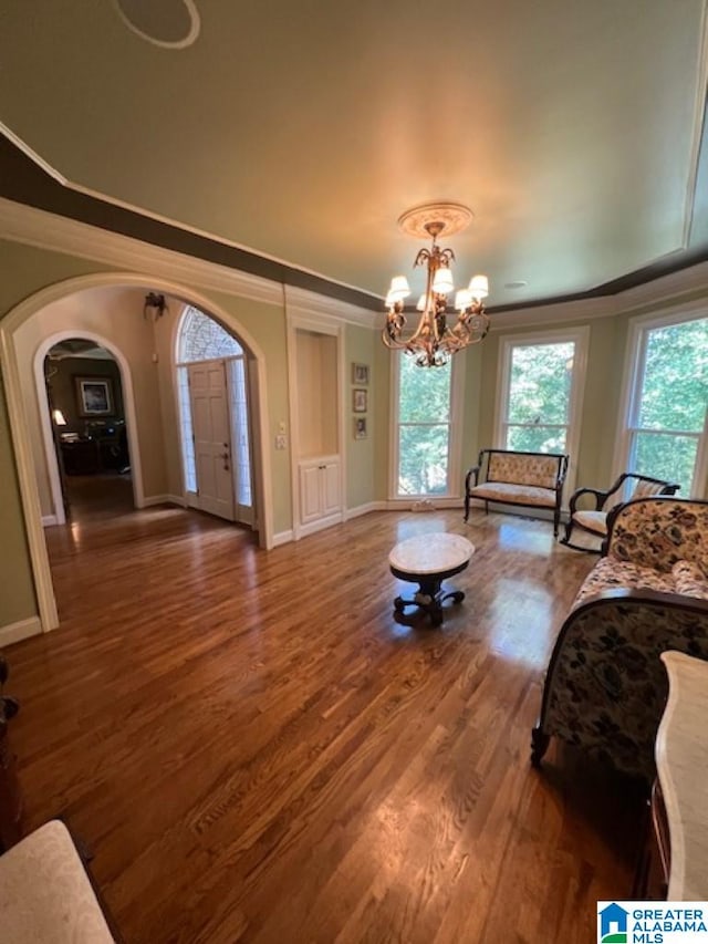 living room featuring a chandelier, dark wood-type flooring, and crown molding