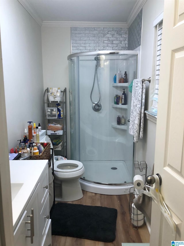 bathroom featuring vanity, ornamental molding, toilet, a shower with door, and hardwood / wood-style floors