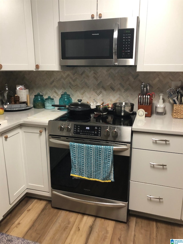 kitchen with appliances with stainless steel finishes, light hardwood / wood-style floors, white cabinetry, and tasteful backsplash