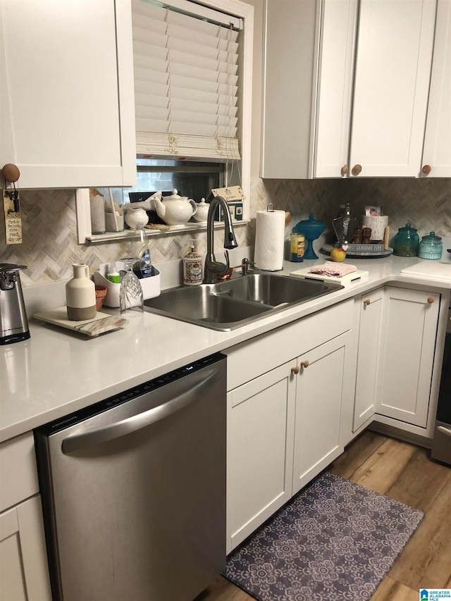 kitchen with dishwasher, hardwood / wood-style flooring, tasteful backsplash, sink, and white cabinetry