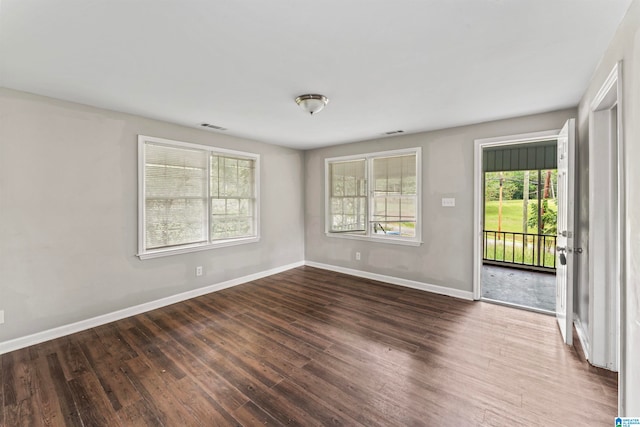 empty room featuring plenty of natural light and dark hardwood / wood-style flooring