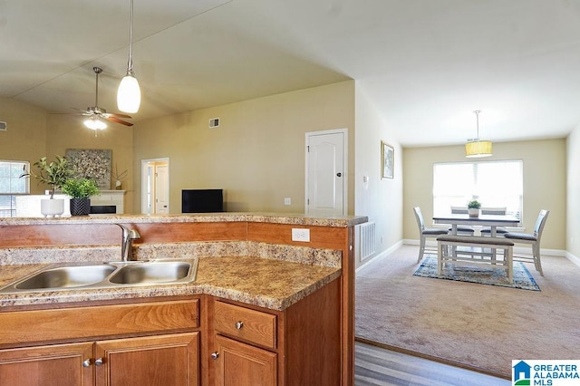 kitchen with sink, hanging light fixtures, light colored carpet, and ceiling fan