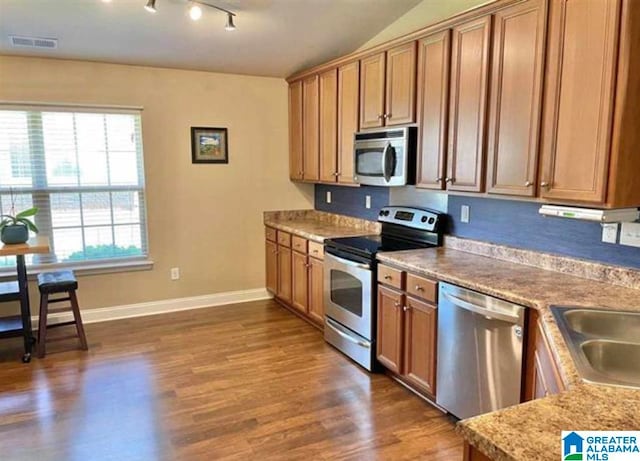 kitchen with dark hardwood / wood-style floors, stainless steel appliances, sink, and light stone counters