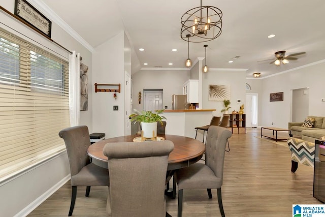 dining space with ceiling fan with notable chandelier, light hardwood / wood-style floors, and ornamental molding