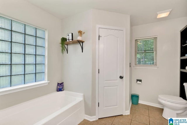 bathroom with a wealth of natural light, tile patterned flooring, toilet, and a tub