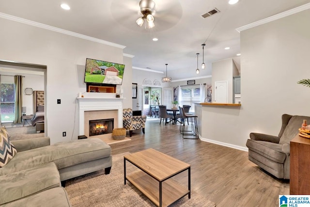 living room with crown molding, light hardwood / wood-style floors, and ceiling fan