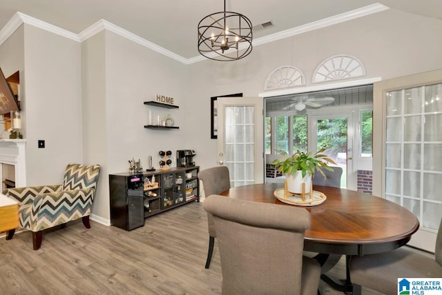 dining room featuring light wood-type flooring, crown molding, and ceiling fan with notable chandelier