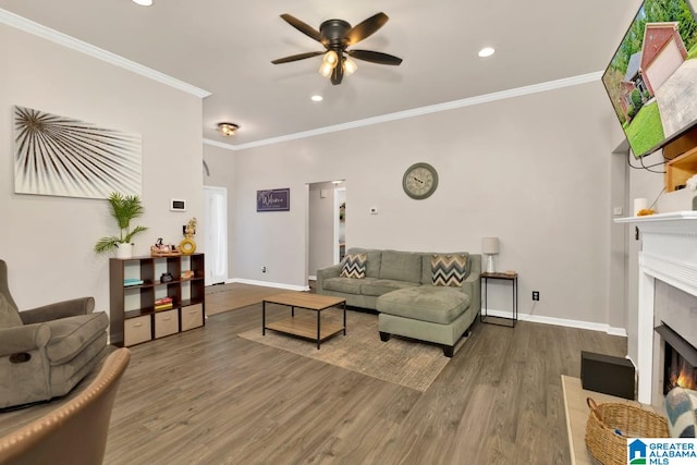 living room featuring a fireplace, ornamental molding, ceiling fan, and dark wood-type flooring