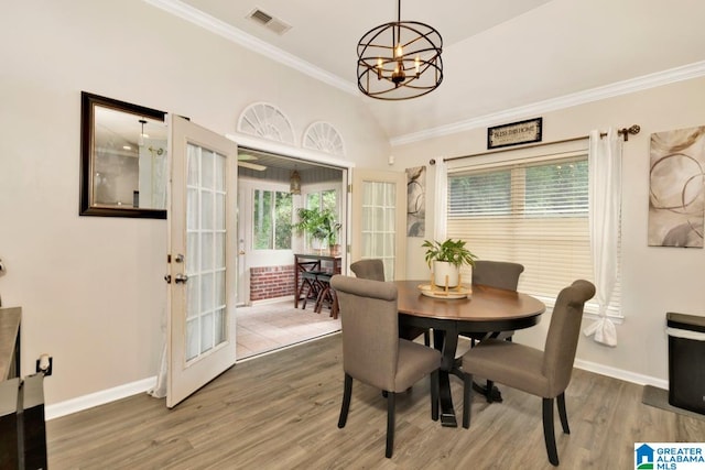 dining area featuring vaulted ceiling, dark hardwood / wood-style flooring, crown molding, french doors, and a chandelier