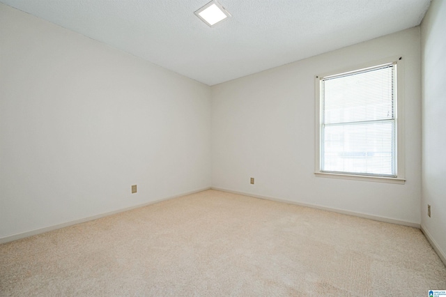 spare room with a textured ceiling and light colored carpet