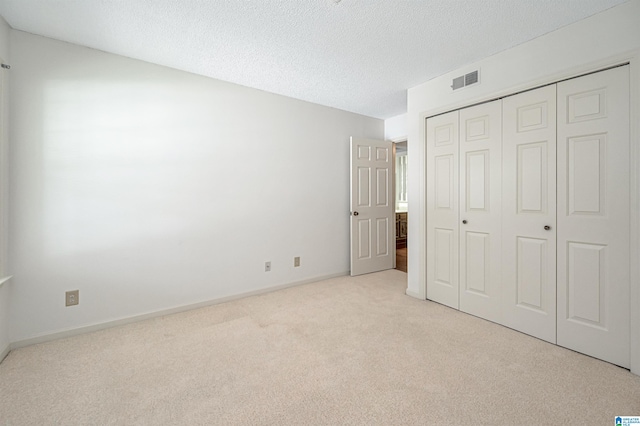 unfurnished bedroom with light carpet, a closet, and a textured ceiling