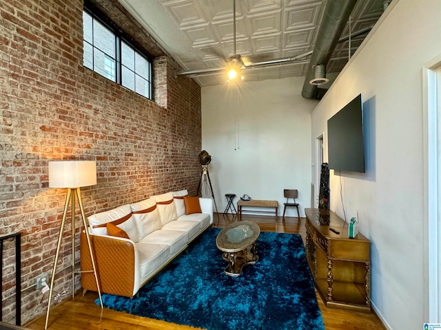 living room featuring wood-type flooring and brick wall