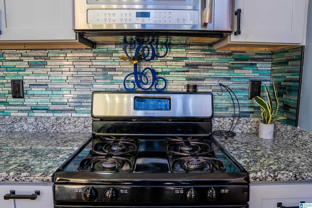 kitchen with black range with gas stovetop, tasteful backsplash, and white cabinetry