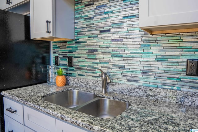 kitchen with white cabinets, light stone countertops, sink, and tasteful backsplash