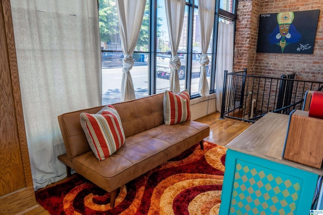 living room with a healthy amount of sunlight, hardwood / wood-style floors, and brick wall