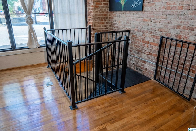 stairway with brick wall and hardwood / wood-style floors