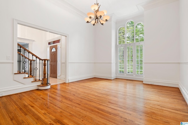 unfurnished room with a chandelier, light hardwood / wood-style floors, and crown molding