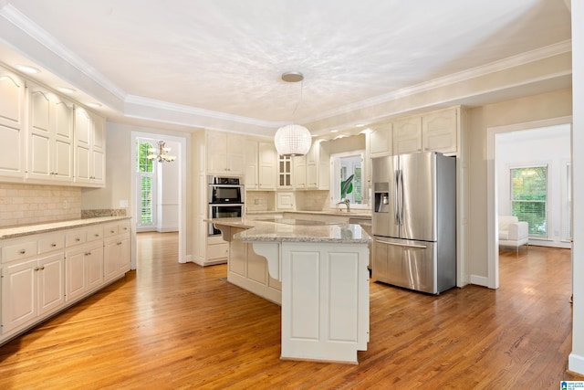 kitchen with light wood-type flooring, a center island, tasteful backsplash, hanging light fixtures, and stainless steel appliances